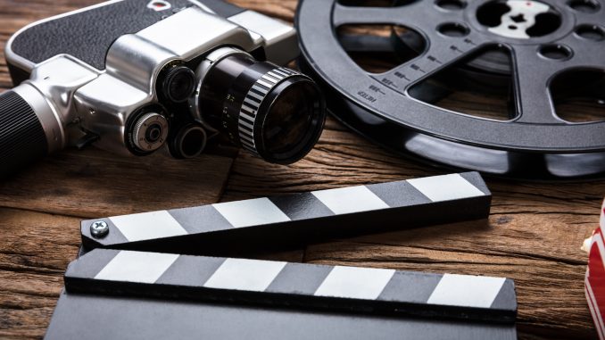 Movie Camera With Film Reel And Clapper Board On Wood